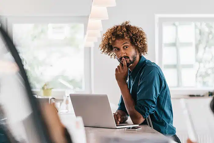 un hombre pensativo mientras utiliza su computador portatil